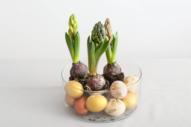 Скляний горщик з красивими рослинами гіацинта та великодніми яйцями на світлому фоні
 - Фото, зображення