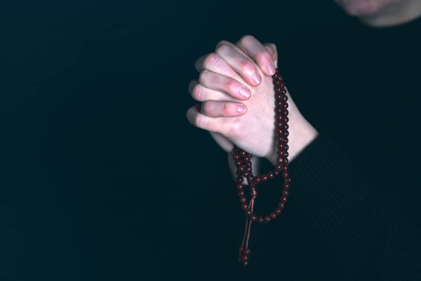Religious young woman praying to God, on dark background. - Foto, Bild