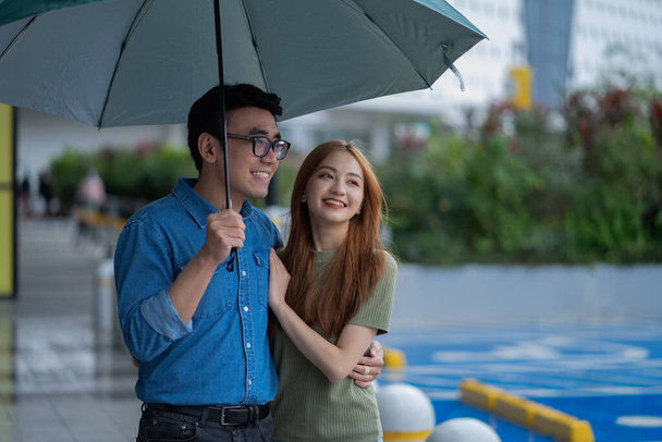 Joven pareja asiática caminando bajo la lluvia - Foto, Imagen