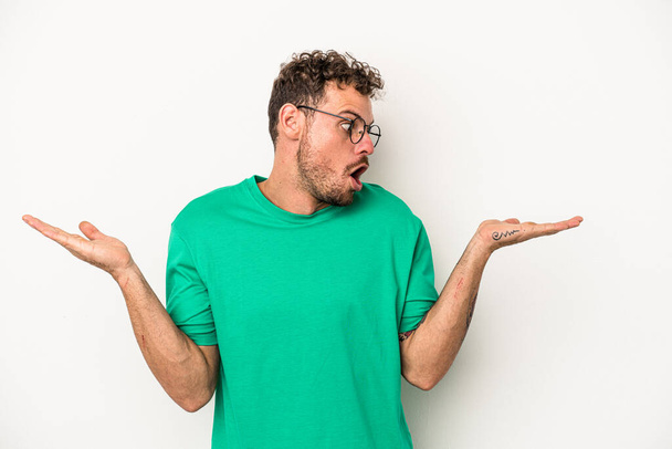 Young caucasian man isolated on white background confused and doubtful shrugging shoulders to hold a copy space. - Photo, Image