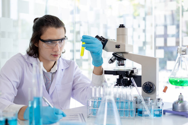 Laboratorio diagnoosi synteettisiä aineita, Tutkija tai tutkija tutkii aineen in vitro ja tallentaa tietoja, Laboratoriokokeet, Tutkijat tutkija työskentelee analyysi koeputki. - Valokuva, kuva