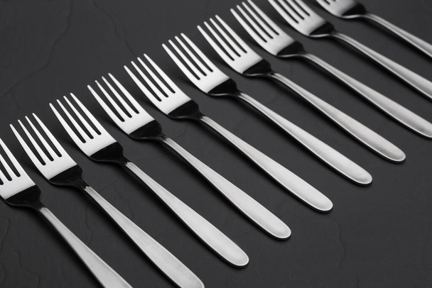 many steel forks lined up on black slate, concept - Foto, Bild