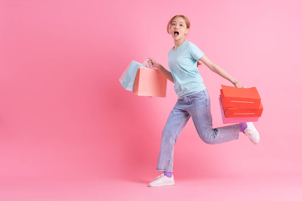 Young Asian woman holding shopping bag on pink background - Foto, afbeelding