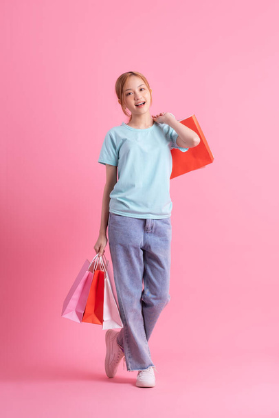 Junge Asiatin mit Einkaufstasche auf rosa Hintergrund - Foto, Bild