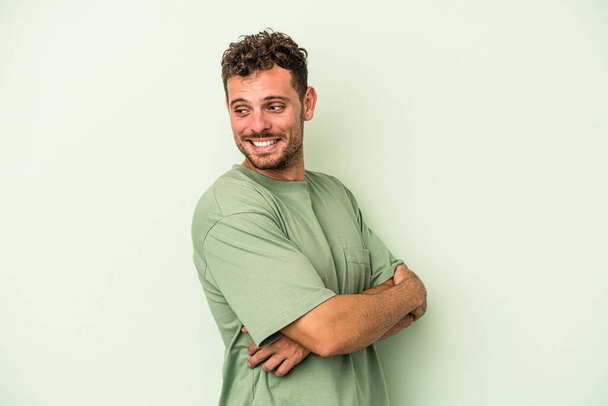 Νεαρός καυκάσιος άνδρας απομονωμένος στο πράσινο φόντο γελώντας και διασκεδάζοντας. - Φωτογραφία, εικόνα