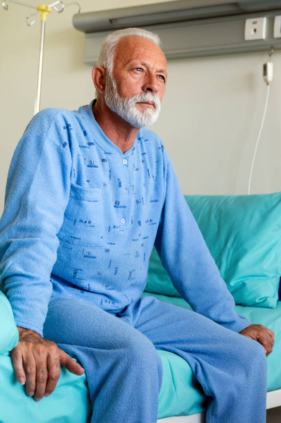 Απελπισμένος ηλικιωμένος ασθενής στο κρεβάτι του νοσοκομείου που αναρρώνει από την ασθένεια. Healthcare, coronavirus, άνθρωποι έννοια. - Φωτογραφία, εικόνα