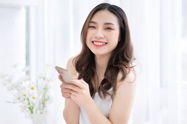 Young Asian woman using smartphone at home in the morning - Foto, imagen