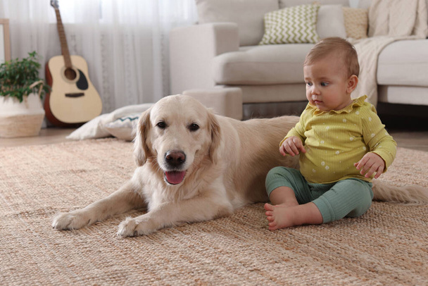 Cute little baby with adorable dog on floor at home - Фото, зображення