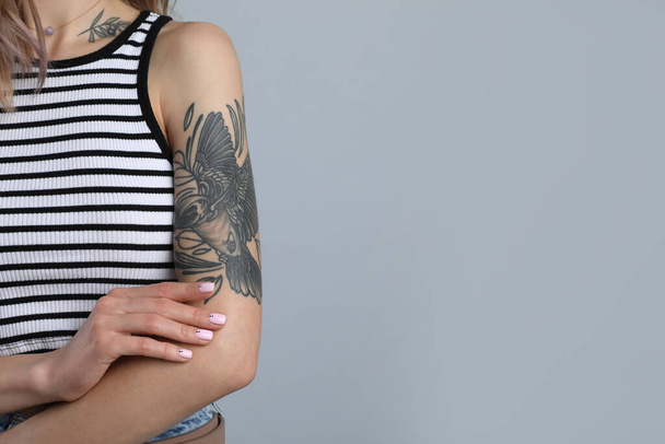 Beautiful woman with tattoos on body against grey background, closeup. Space for text - Fotoğraf, Görsel