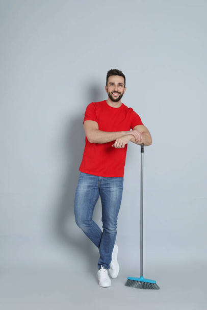 Handsome man with broom on grey background - Photo, Image