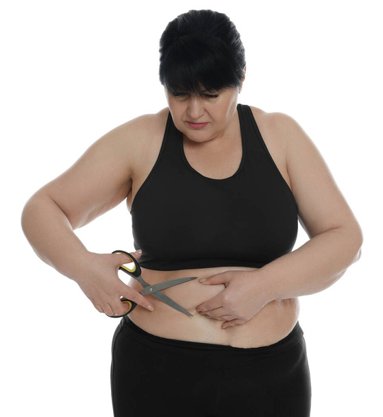 Obese woman with scissors on white background. Weight loss surgery - Photo, Image