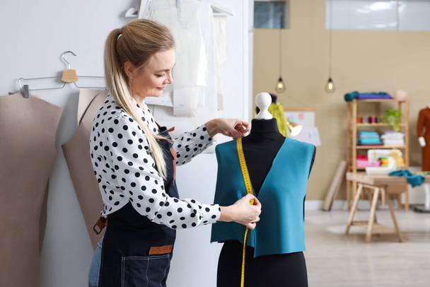 Dressmaker with measuring tape working in atelier - Photo, image