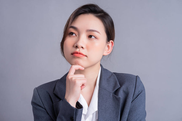 Portrait of a beautiful Asian businesswoman on a gray background - Fotoğraf, Görsel