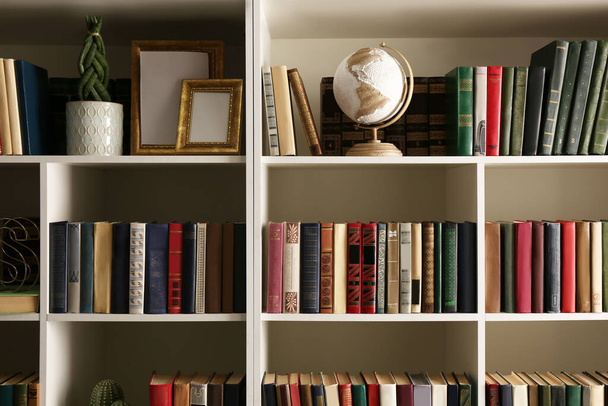 Collection of books and decor elements on shelves. Home library - Foto, immagini