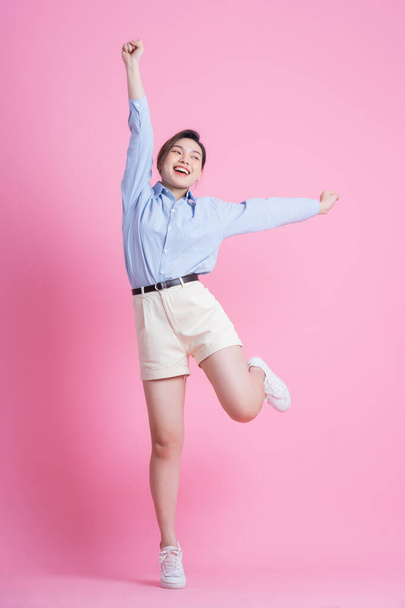 Full length image of young Asian woman posing on pink background - Foto, afbeelding