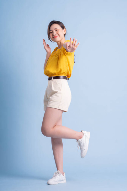 Full length image of young Asian woman posing on blue background - Foto, Imagem