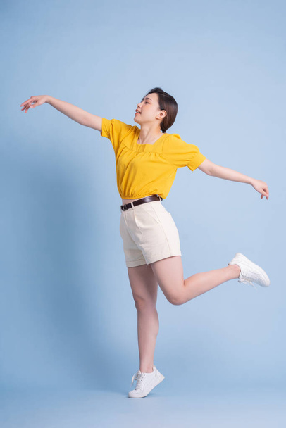 Full length image of young Asian woman posing on blue background - Zdjęcie, obraz