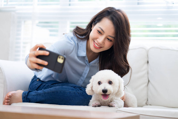 Joven mujer asiática jugando con perro en casa - Foto, Imagen