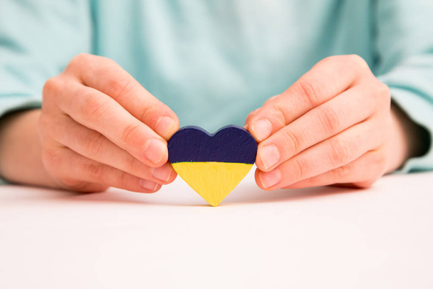 High angle view of child hands holding ukraine flag painted heart - Foto, Bild