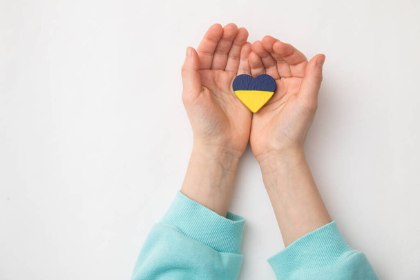 High angle view of child hands holding ukraine flag painted heart - 写真・画像