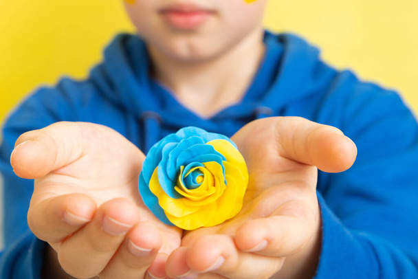 Rose of yellow and blue colors of the Ukrainian flag in the hands of a boy - Photo, Image