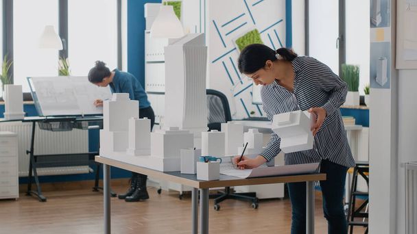 Contractor holding building model to design blueprints plan on table - Photo, Image