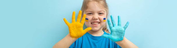 Banner with yellow blue paint on childrens palms. Ukrainian flag symbols concept. Happy ukrainian girl - Foto, afbeelding