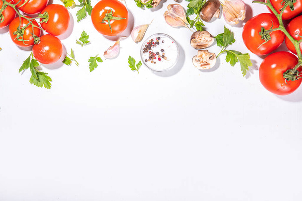 Hintergrund der Zubereitung von Lebensmitteln. Küchentisch Hintergrund mit Gewürzen, Kräutern, Gemüse. Petersilie, Zwiebeln, Knoblauch, Tomaten, Salz, Olivenöl auf weißem Hintergrund - Foto, Bild