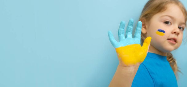 Yellow blue paint on the hand of a little girl. Ukrainian flag symbols concept. Copy space. - Foto, Imagem