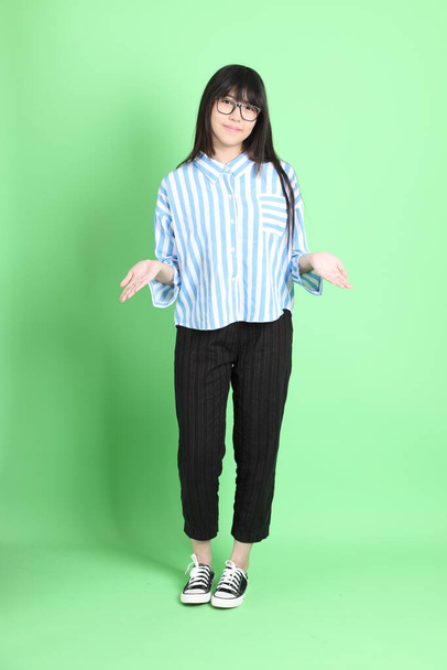 The young Asian girl in casual dressed standing on the green background. - Photo, Image