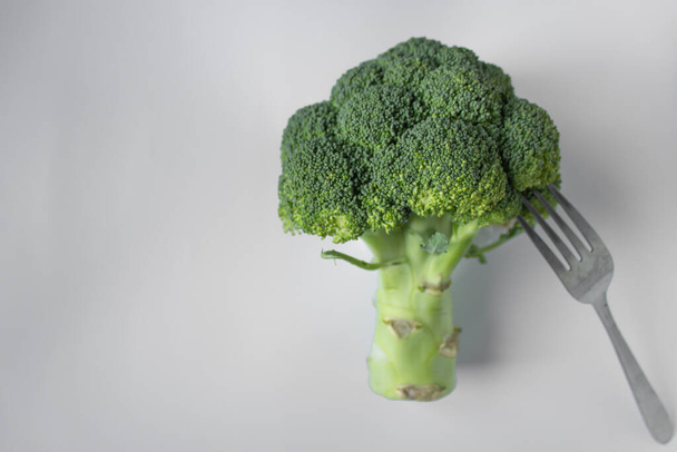 Ramo verde crudo de brócoli recogido en un tenedor, aislado sobre fondo blanco. Día de ayuno y desintoxicación, concepto vegetariano. - Foto, Imagen