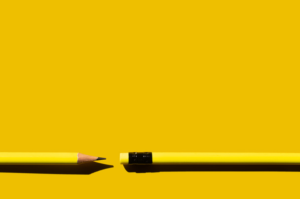 bovenaanzicht van scherpe potloden en gum op gele achtergrond  - Foto, afbeelding
