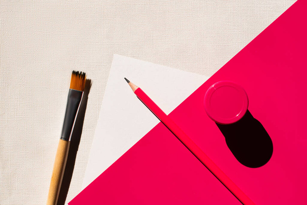 widok z góry pędzel, ołówek i słoik z farbą na białym i różowym  - Zdjęcie, obraz