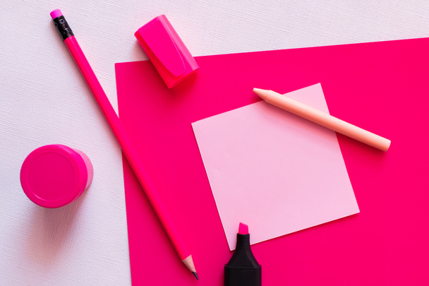 πάνω άποψη της γραφικής ύλης και βάζο με χρώμα κοντά σε κενό χαρτί σημείωμα σε υφή λευκό και ροζ - Φωτογραφία, εικόνα