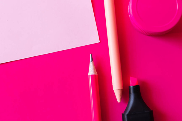 πάνω άποψη της γραφικής ύλης και βάζο με χρώμα κοντά σε χαρτί σημείωμα σε ροζ - Φωτογραφία, εικόνα