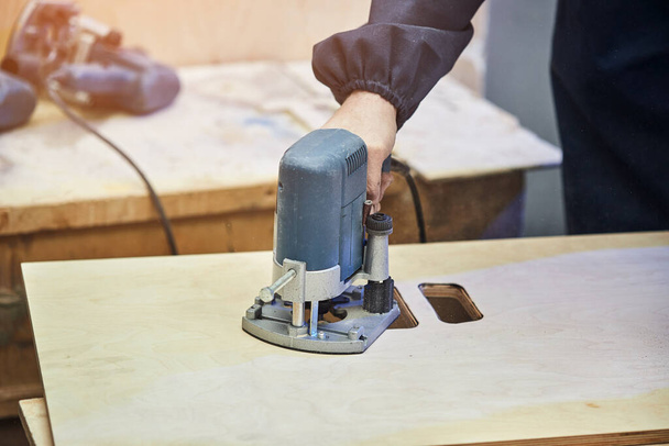 timmerman werken met freesmachine. Joinery, houtbewerking en meubelmakerij, professionele timmerman hout snijden in timmerwerk werkplaats, industrieel concept. - Foto, afbeelding