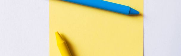 vue de dessus des crayons bleus et jaunes près de la note de papier isolé sur blanc, bannière - Photo, image