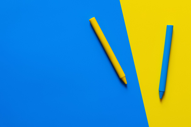 top view of crayons on blue and yellow background  - Foto, imagen
