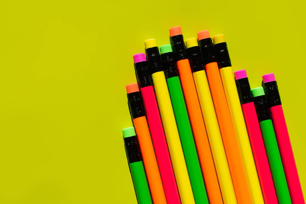 vista superior de lápices de colores con borradores sobre fondo verde  - Foto, imagen