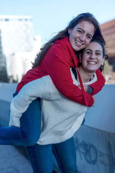 Half length of two blonde and redhead women friends having fun outdoor in the city, riding piggyback - happiness, friendship, having fun concept - Zdjęcie, obraz