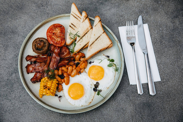 İngiliz kahvaltısı. Pastırmalı yumurta, fasulye, mısır ve sebze.. - Fotoğraf, Görsel