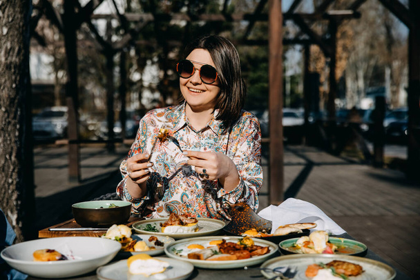 Glückliche Frau frühstückt auf einer Terrasse im Sonnenlicht. - Foto, Bild