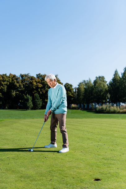 asian senior man holding golf club while playing outdoors  - Zdjęcie, obraz