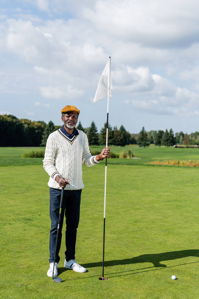 riche homme âgé afro-américain debout avec bâton de drapeau et club de golf  - Photo, image