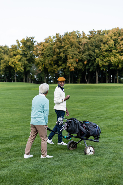 senior african american man walking near friend with golf cart  - Photo, Image