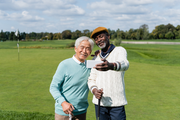 afro-amerikai férfi szelfit készít idős boldog ázsiai barátjával  - Fotó, kép