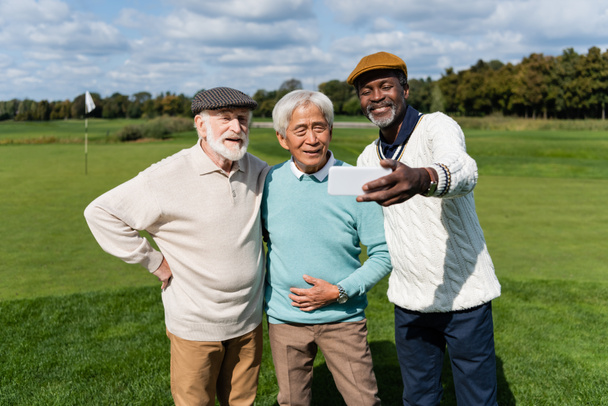 gelukkig afrikaanse amerikaanse man nemen selfie met senior interraciale vrienden   - Foto, afbeelding