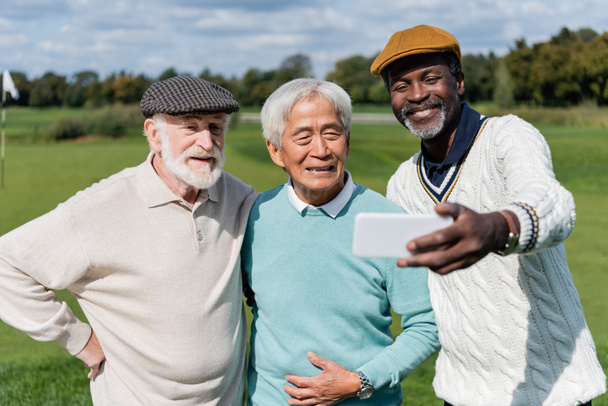 alegre afroamericano hombre tomando selfie con senior interracial amigos   - Foto, Imagen