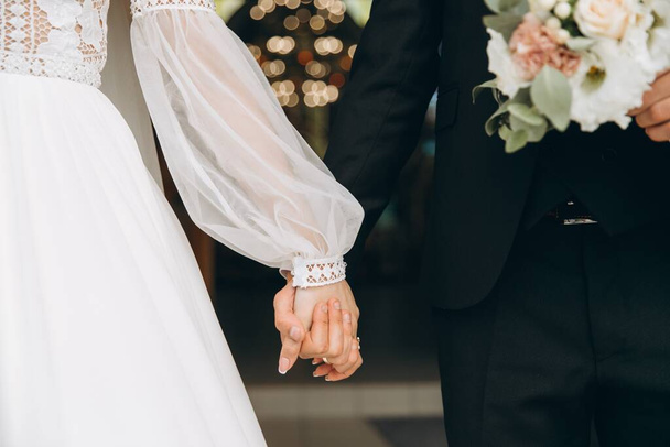 День весілля. Наречений тримає руку нареченої на фоні боке
. - Фото, зображення