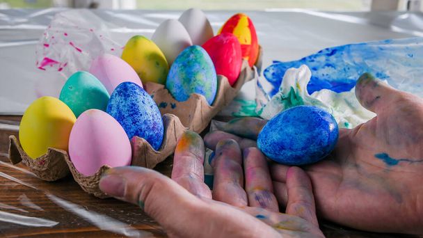 Mano sucia con huevo de Pascua pintado y otra variación de huevos - Foto, Imagen